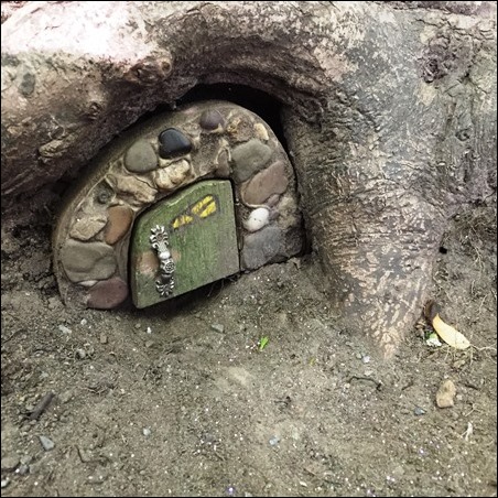 house on the ground, with a little painted door and rocks around the frame